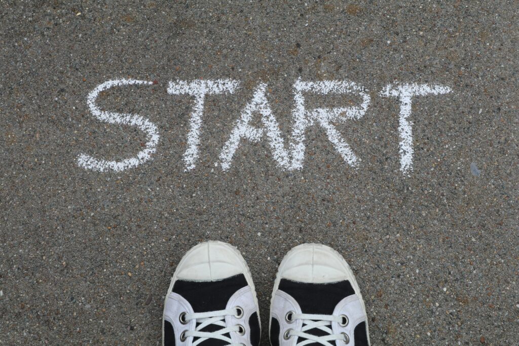 Close-up of sneakers and a 'START' chalk drawing on pavement, symbolizing new beginnings.